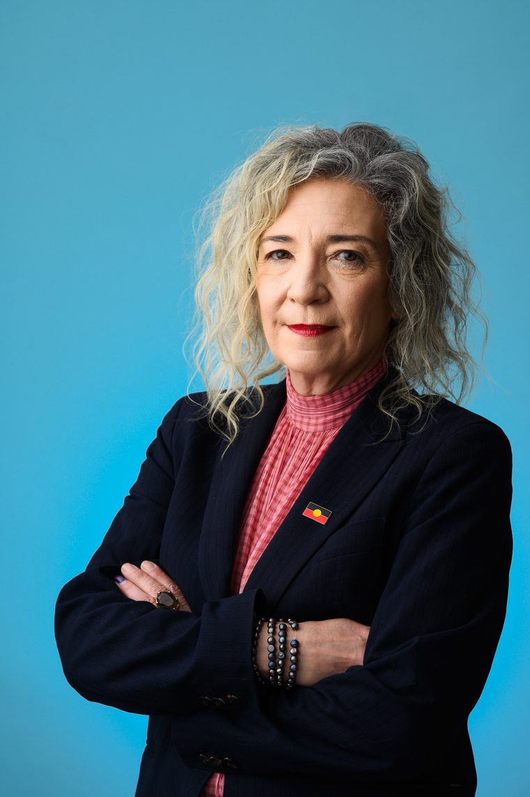 Melissa Lowe, arms folded, wearing an Aboriginal flag pin